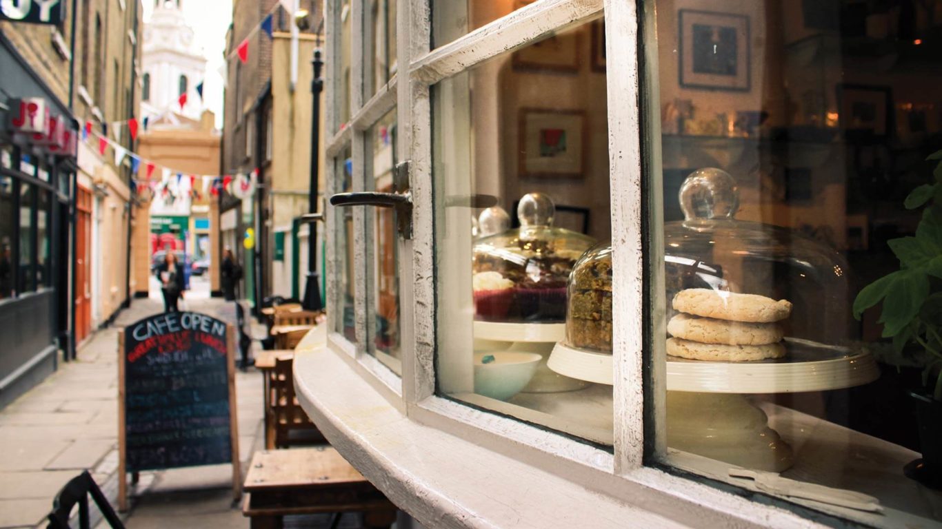 Quaint cafe view with pastries and cobblestone street, offering a charming, cosy experience at The Clarendon.