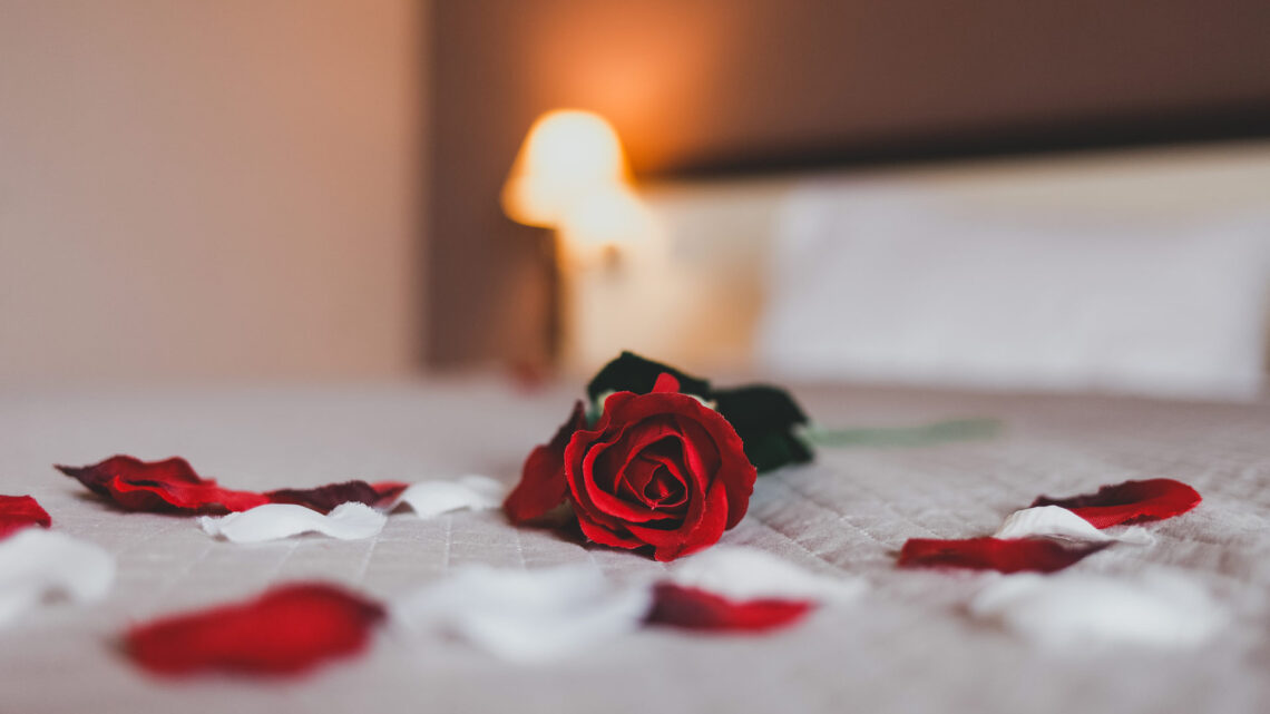 Elegant hotel room bed with rose petals and soft lighting, perfect for romantic getaways at The Clarendon.