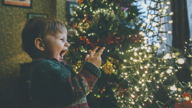 Little boy playing with Christmas lights at home