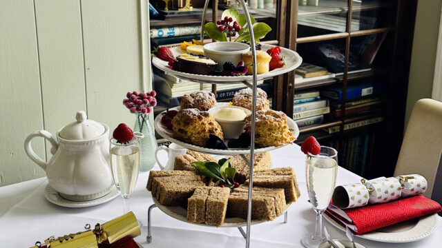 Elegant afternoon tea setup with scones, sandwiches, and pastries at The Clarendon, accompanied by tea and sparkling drinks.
