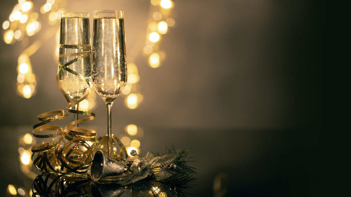 Elegant champagne glasses with festive ribbons and lights, celebrating luxury at The Clarendon.