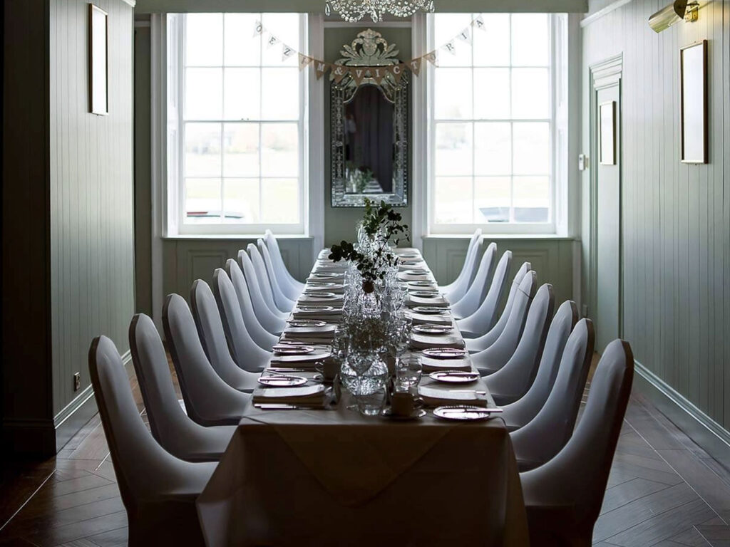 Elegant Dining Room Setup Elegant dining room with long table, set for events, natural light from large windows, perfect for gatherings at The Clarendon.