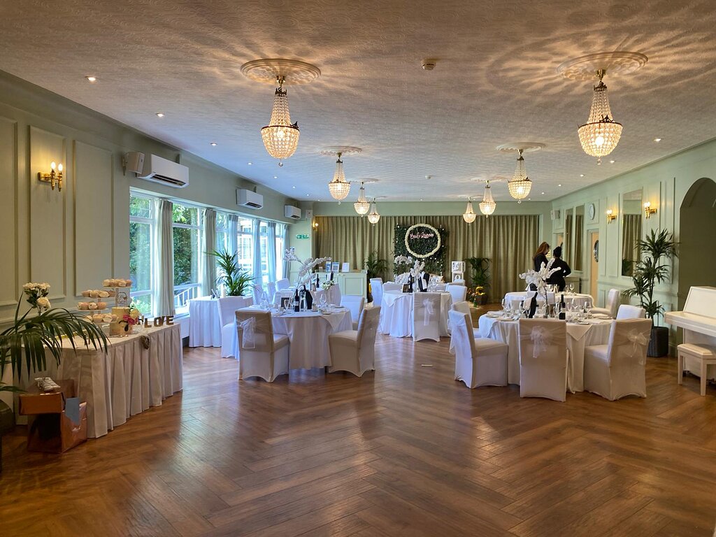 Elegant Banquet Venue Elegant banquet hall at The Clarendon with chandeliers, wood flooring, round tables, and garden views for special events.