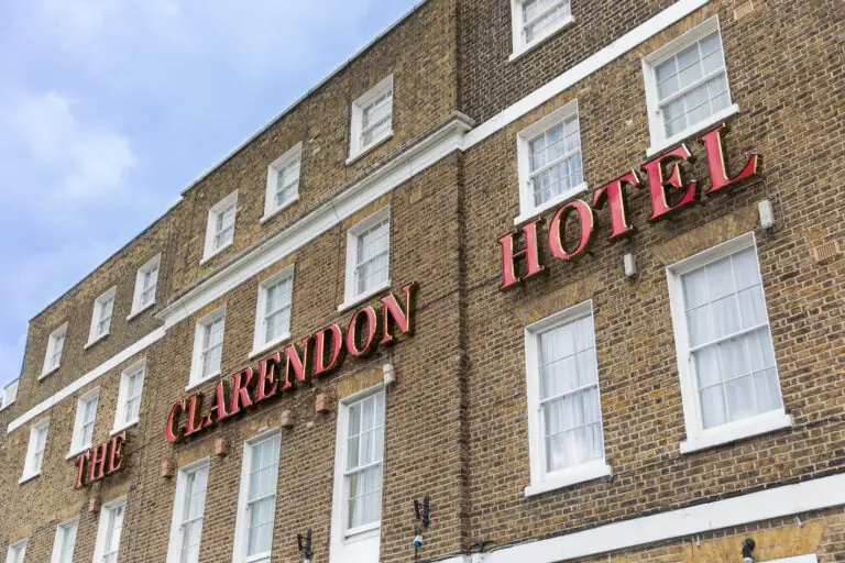 Classic brick facade of The Clarendon Hotel with bright red signage, inviting guests for a cosy stay in elegant surroundings.