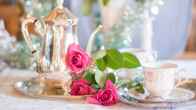 Elegant silver teapot, roses, and fine china for afternoon tea at The Clarendon, promising luxury and refined relaxation.