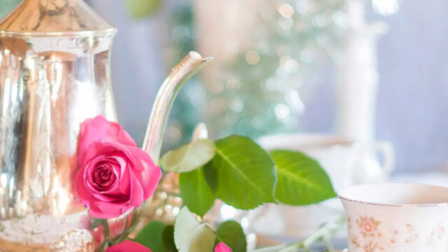 Elegant tea setting with silver teapot, pink roses, and fine china at The Clarendon, offering a luxurious afternoon tea experience.