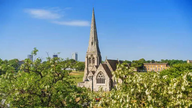 Stunning view from The Clarendon of a historic church spire, lush greenery, and vibrant blue sky; a tranquil, picturesque setting.
