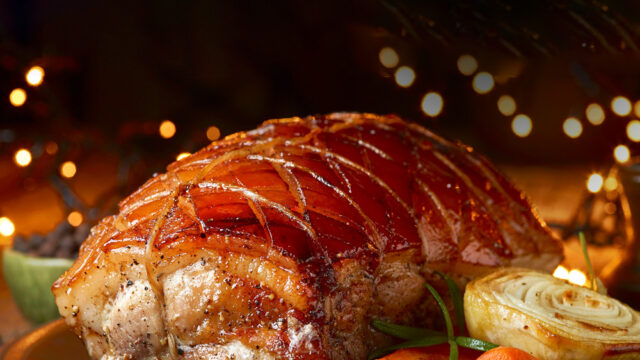 Succulent roast pork with crispy crackling, garnished with carrots and herbs, set in an ambient, elegant Clarendon restaurant.