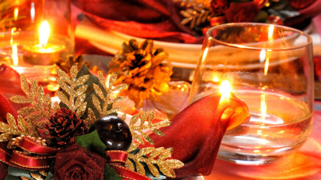 Festive table setting with glowing candles, elegant red napkins, and golden decorations at The Clarendon hotel restaurant.