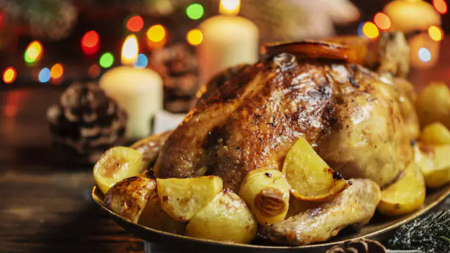 Festive roast chicken with golden potatoes, lit by candlelight, creating a cosy dining experience at The Clarendon Hotel.