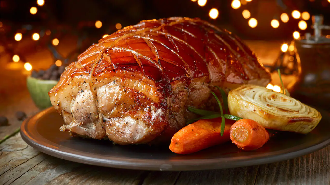 Succulent roast pork with caramelised carrots and onion, served at The Clarendon. Enjoy fine dining with festive ambience.